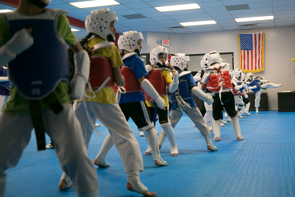 Girls and boys practicing martial arts, taekwondo, karate, and self defense in class.